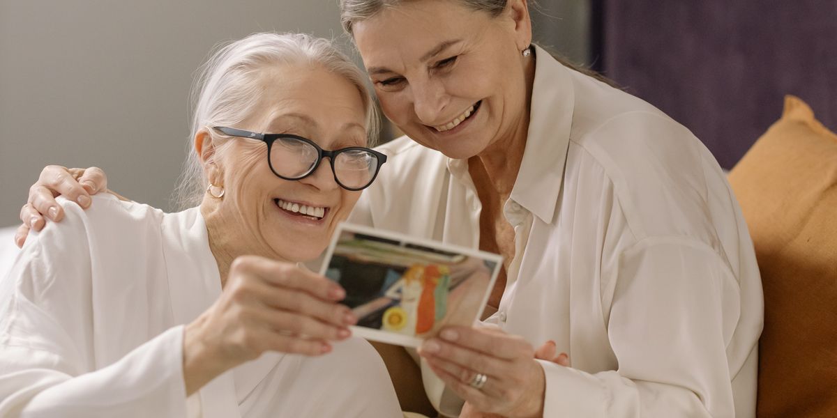 Two seniors smiling over an old photo album