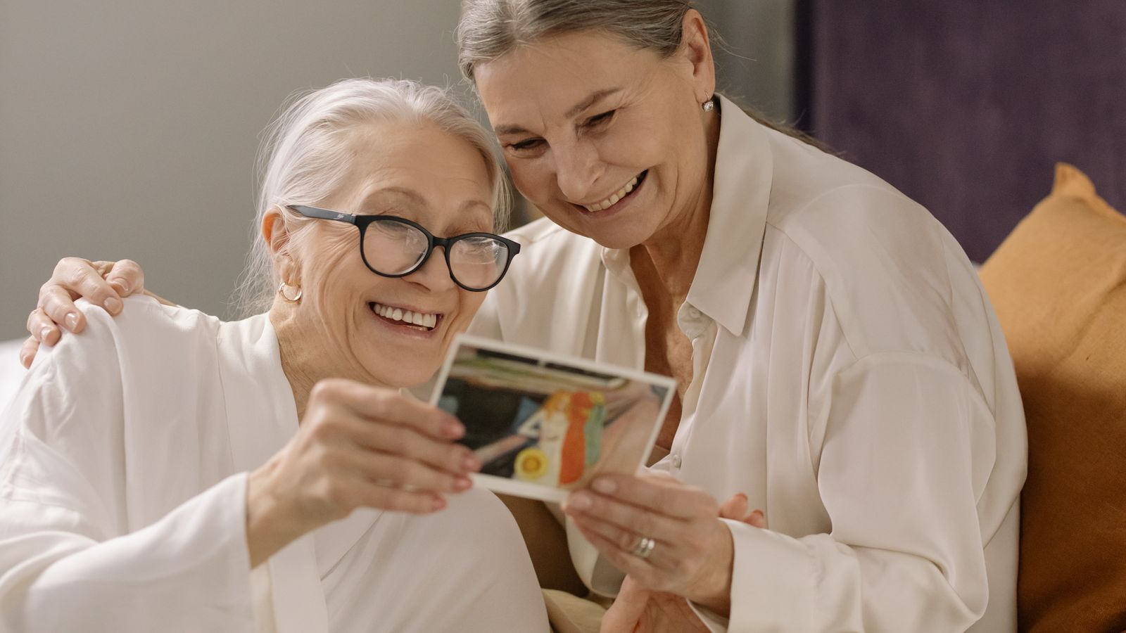 Two women smiling over an old photograph